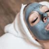 A woman wearing a black facial mask, showcasing a skincare treatment