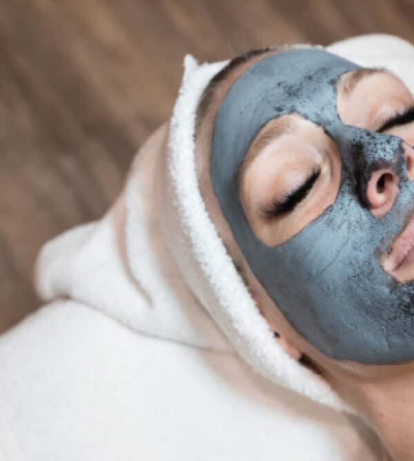 A woman wearing a black facial mask, showcasing a skincare treatment