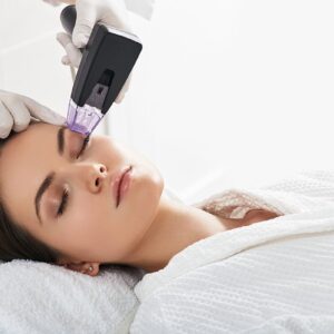 A woman having her eyebrows groomed with a machine at a beauty studio